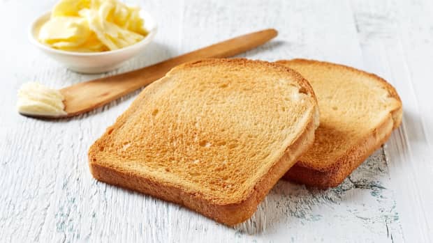 Two slices of toasted bread with a wooden knife and butter.